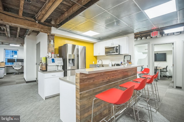 kitchen with a center island, white cabinets, sink, appliances with stainless steel finishes, and a kitchen bar