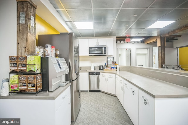 kitchen featuring white cabinets, appliances with stainless steel finishes, and a drop ceiling