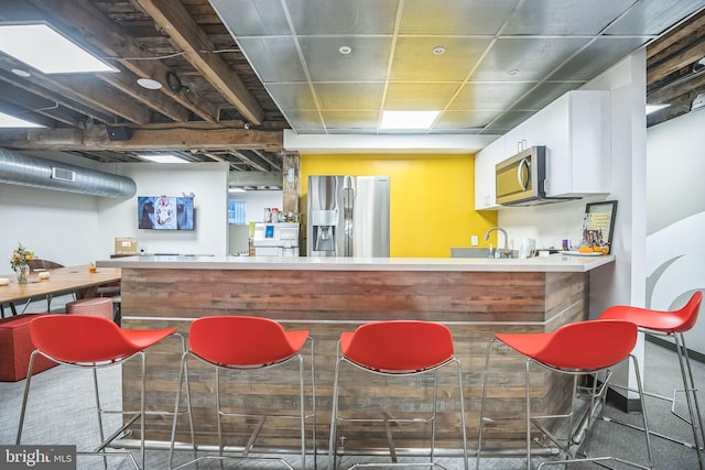 bar with white cabinets, appliances with stainless steel finishes, and sink