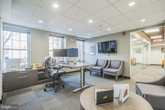 office space with a drop ceiling and light colored carpet