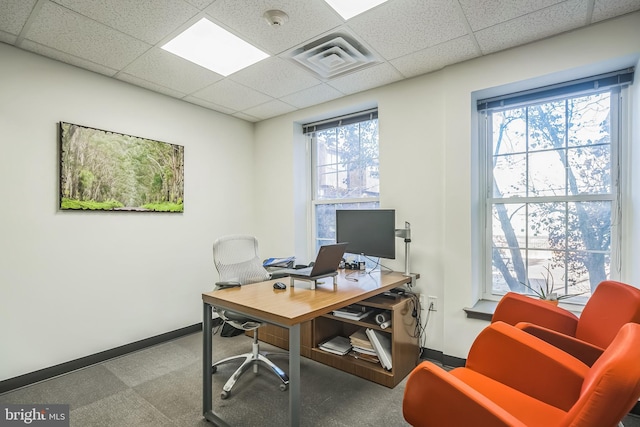 home office featuring a paneled ceiling, carpet flooring, and a healthy amount of sunlight