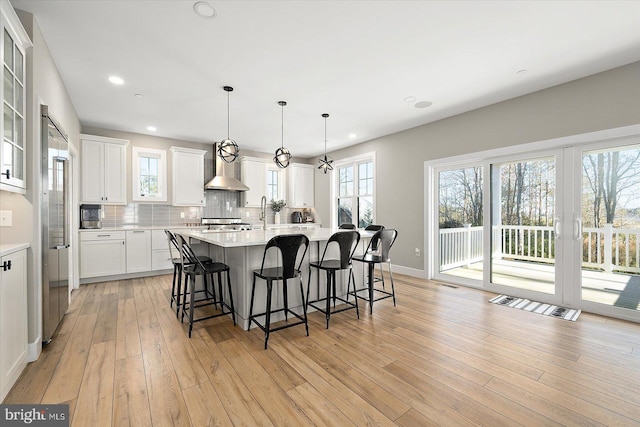 kitchen with white cabinets, light hardwood / wood-style floors, decorative light fixtures, and a kitchen island