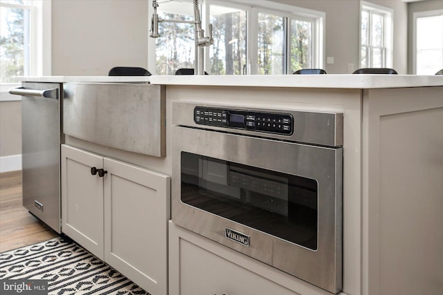 kitchen featuring white cabinetry, an inviting chandelier, light hardwood / wood-style floors, and appliances with stainless steel finishes