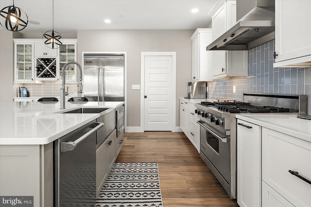 kitchen with white cabinetry, high quality appliances, dark wood-type flooring, and wall chimney range hood