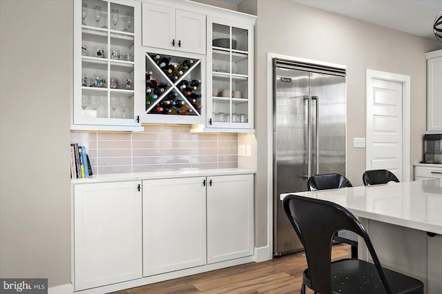 interior space featuring tasteful backsplash, white cabinetry, stainless steel built in fridge, and light hardwood / wood-style floors