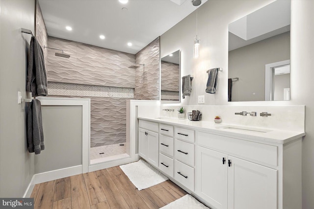 bathroom featuring vanity, wood-type flooring, tile walls, and tiled shower