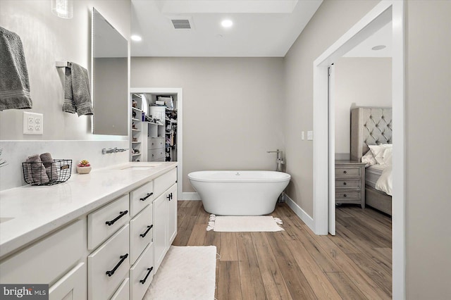 bathroom with a bathing tub, vanity, and wood-type flooring