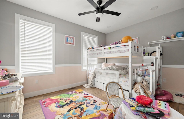 bedroom featuring ceiling fan, light wood-type flooring, and multiple windows