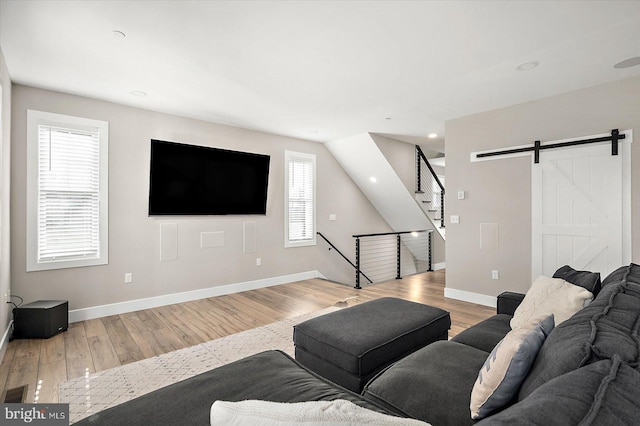 living room with a barn door and light hardwood / wood-style flooring