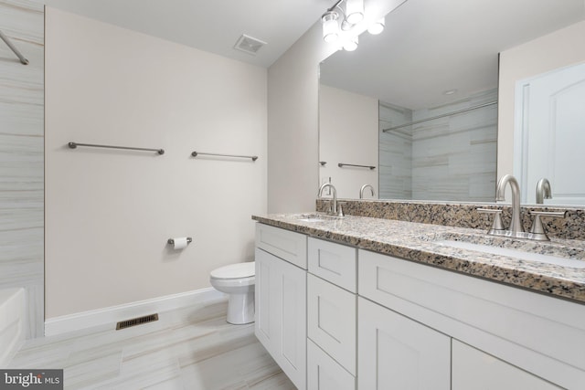 bathroom with a tile shower, vanity, and toilet