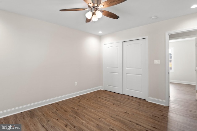 unfurnished bedroom with dark wood-type flooring, a closet, and ceiling fan