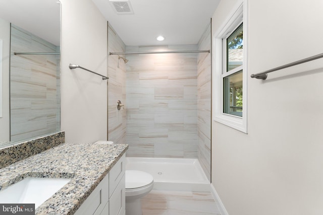 bathroom featuring tiled shower, vanity, and toilet