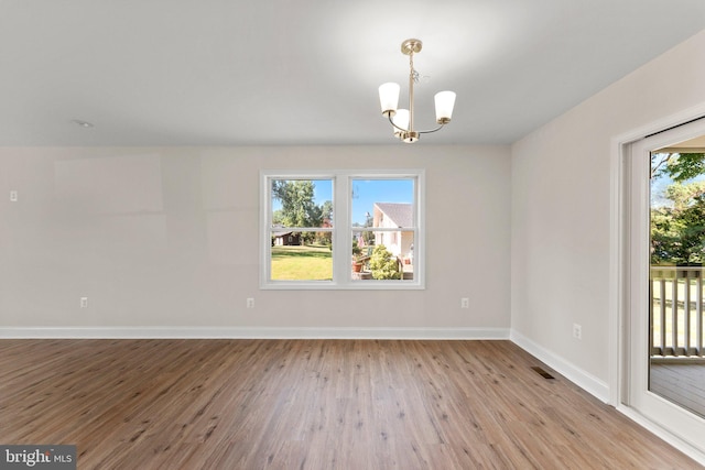 spare room with light hardwood / wood-style flooring and a notable chandelier