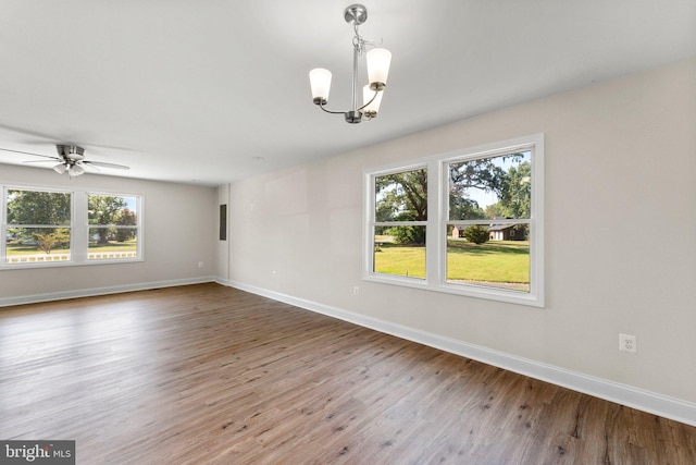 spare room with wood-type flooring and ceiling fan with notable chandelier