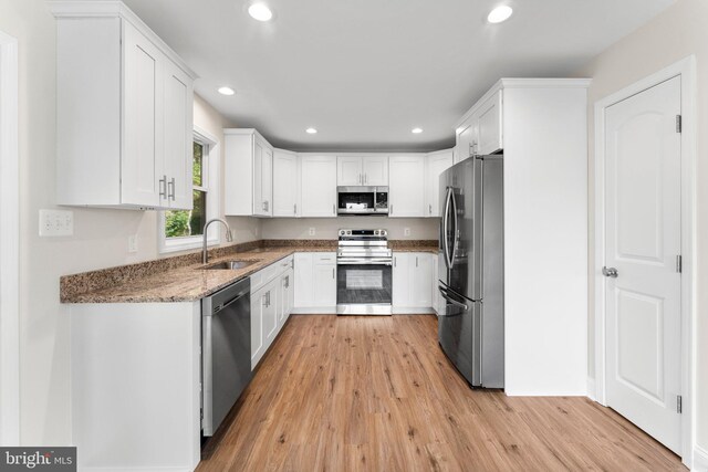 kitchen featuring white cabinets, appliances with stainless steel finishes, sink, and dark stone counters