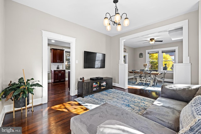 living room with ceiling fan with notable chandelier and dark hardwood / wood-style flooring