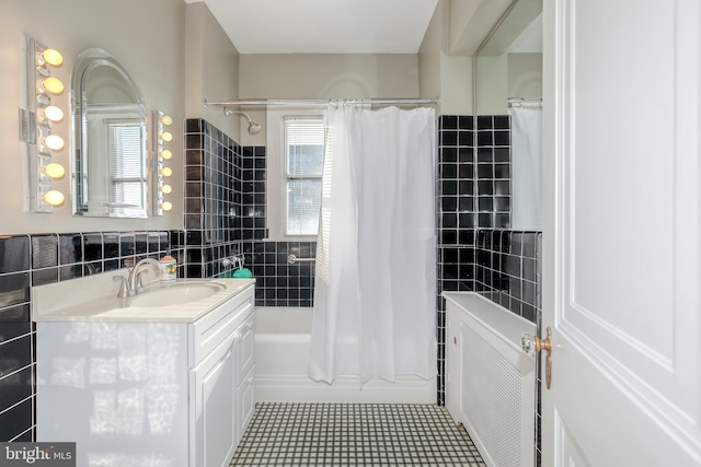bathroom with vanity, radiator, tile patterned floors, shower / bath combo with shower curtain, and tile walls
