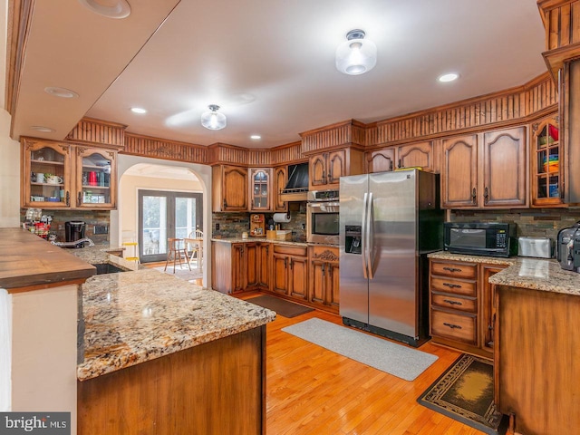 kitchen featuring french doors, light wood-type flooring, tasteful backsplash, kitchen peninsula, and stainless steel appliances