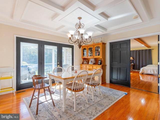 dining room featuring a notable chandelier, light hardwood / wood-style floors, ornamental molding, and coffered ceiling