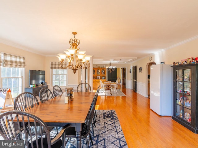 dining room with ornamental molding, light wood-type flooring, and an inviting chandelier