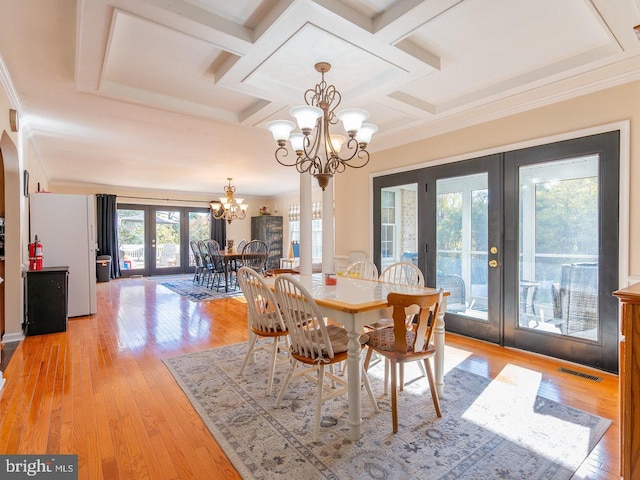 dining space featuring a notable chandelier, light hardwood / wood-style floors, ornamental molding, and french doors