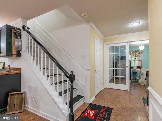 interior space with a textured ceiling and crown molding