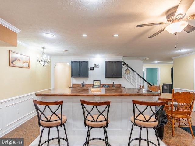 kitchen featuring a textured ceiling, a breakfast bar, kitchen peninsula, and ornamental molding