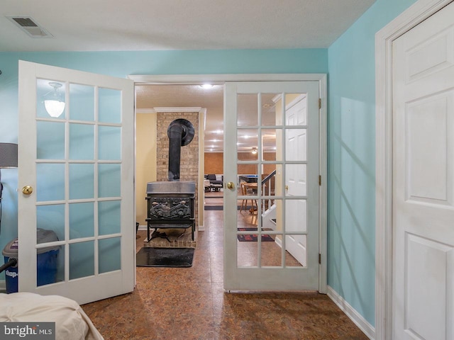 doorway featuring french doors, a textured ceiling, and a wood stove