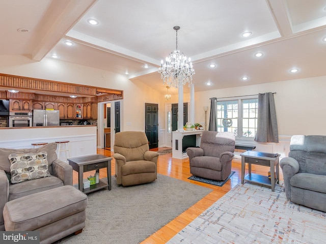 living room featuring vaulted ceiling with beams, light wood-type flooring, and a notable chandelier