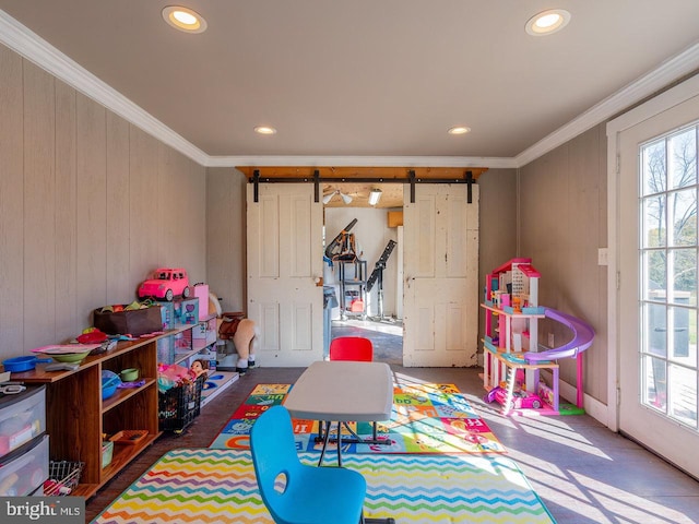 recreation room featuring a barn door and crown molding