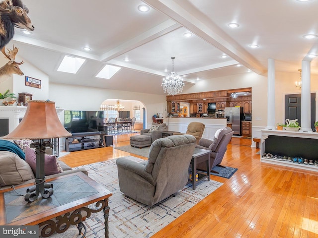 living room with vaulted ceiling with beams, a notable chandelier, and light hardwood / wood-style flooring