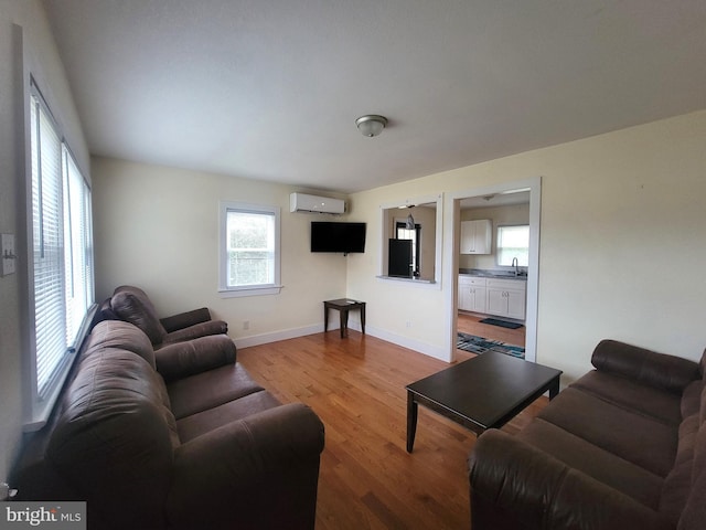 living room featuring light wood-type flooring, sink, and a wall mounted AC