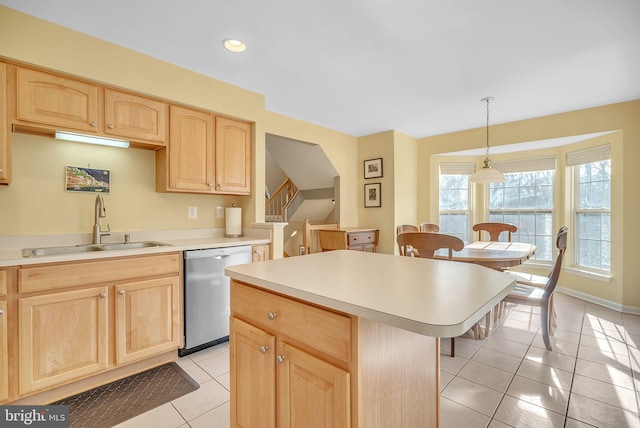 kitchen featuring light brown cabinetry, decorative light fixtures, dishwasher, sink, and a center island