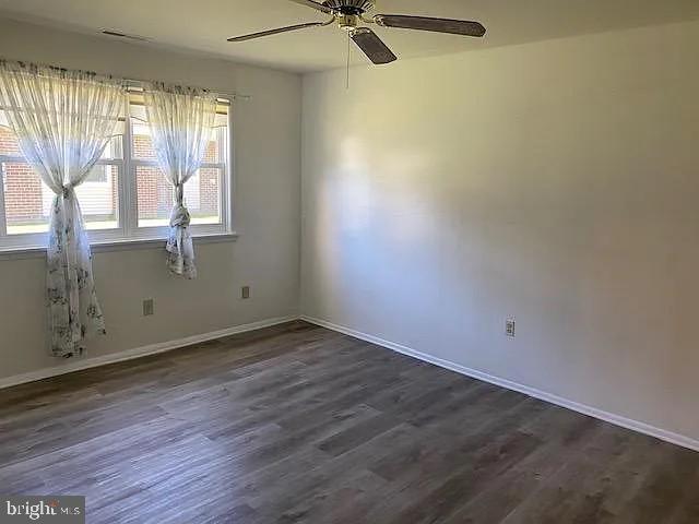 unfurnished room with ceiling fan and dark wood-type flooring