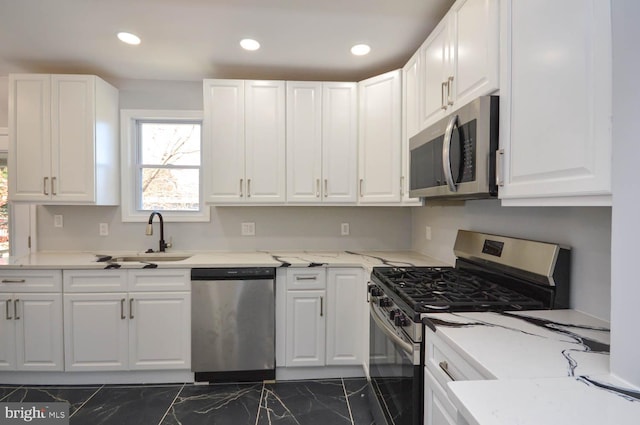 kitchen with white cabinets, stainless steel appliances, light stone countertops, and sink