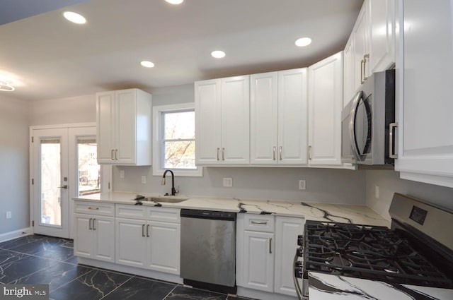 kitchen with sink, french doors, stainless steel appliances, light stone counters, and white cabinets