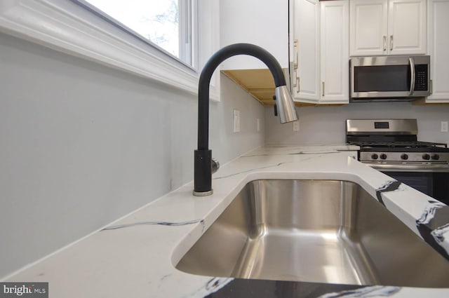 details featuring light stone counters, white cabinets, and stainless steel appliances