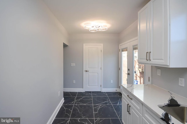 kitchen featuring french doors, white cabinetry, and light stone counters