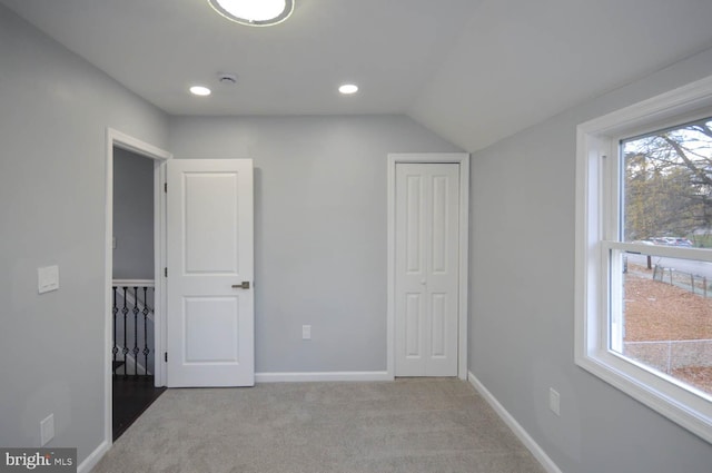 unfurnished bedroom with light carpet and vaulted ceiling