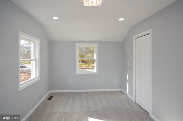 unfurnished room featuring light colored carpet and vaulted ceiling