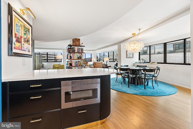 2510 Virginia Ave NW Unit 1104-N, Washington, DC 20037 - kitchen with light wood-style floors, light countertops, a peninsula, a chandelier, and stainless steel microwave