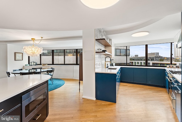 2510 Virginia Ave NW Unit 1104-N, Washington, DC 20037 - kitchen with stainless steel appliances, open shelves, blue cabinetry, light wood finished floors, and a chandelier