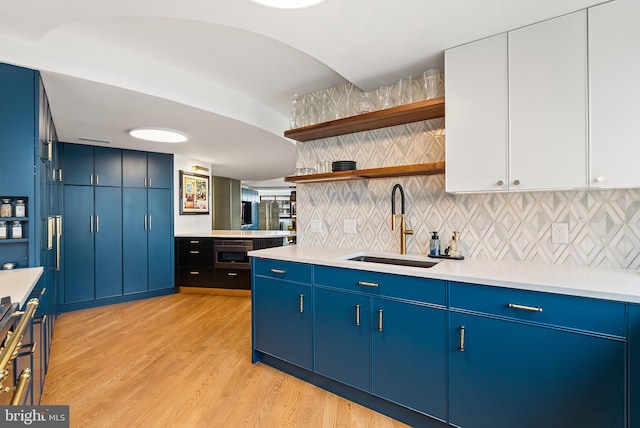 kitchen with light hardwood / wood-style flooring, white cabinetry, blue cabinets, and sink