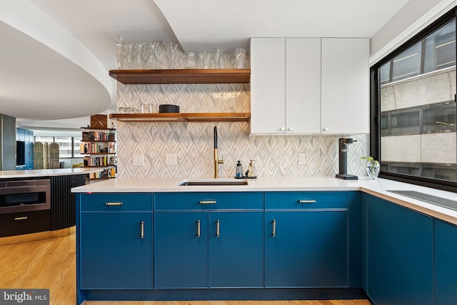 kitchen featuring light hardwood / wood-style floors, white cabinetry, sink, and a wealth of natural light