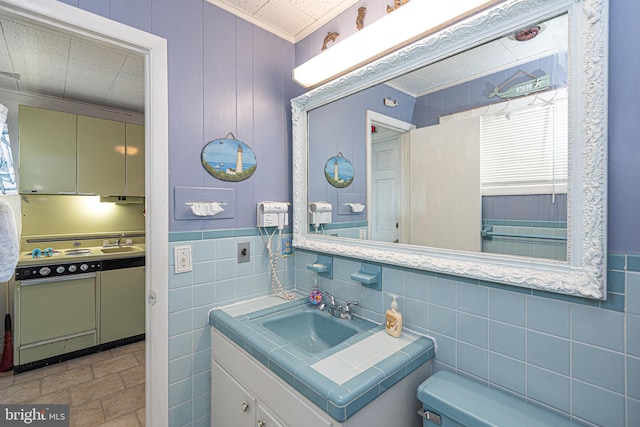 bathroom with vanity, toilet, tile walls, and ornamental molding