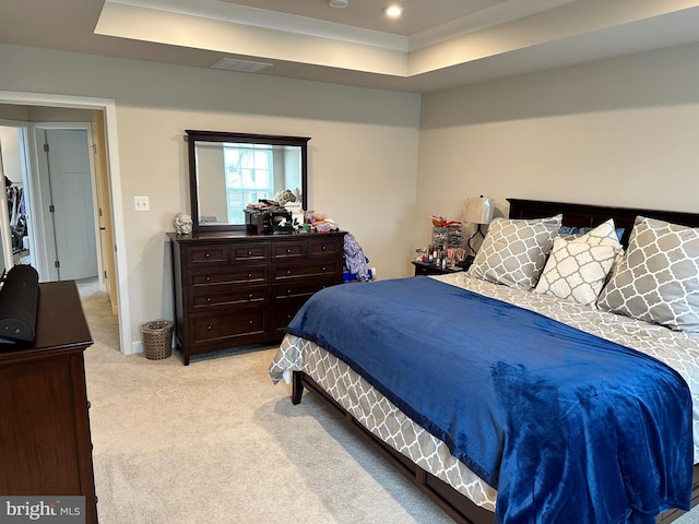 bedroom featuring light colored carpet and a tray ceiling