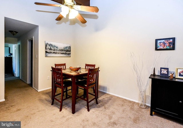 dining space featuring light carpet and ceiling fan