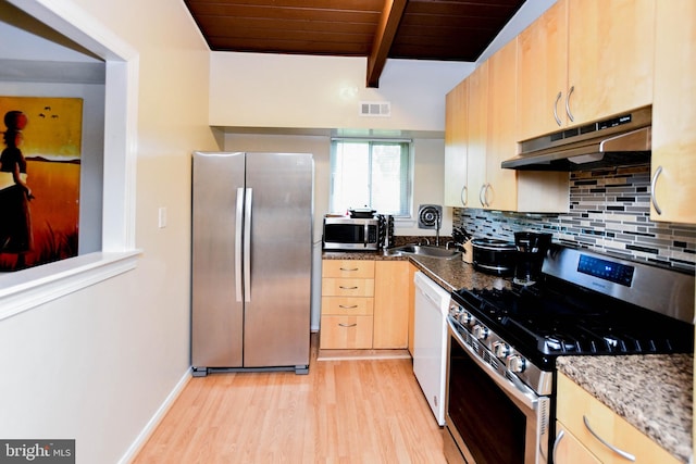 kitchen featuring beamed ceiling, stainless steel appliances, extractor fan, and dark stone countertops