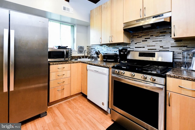 kitchen featuring dark stone counters, sink, light wood-type flooring, light brown cabinetry, and stainless steel appliances