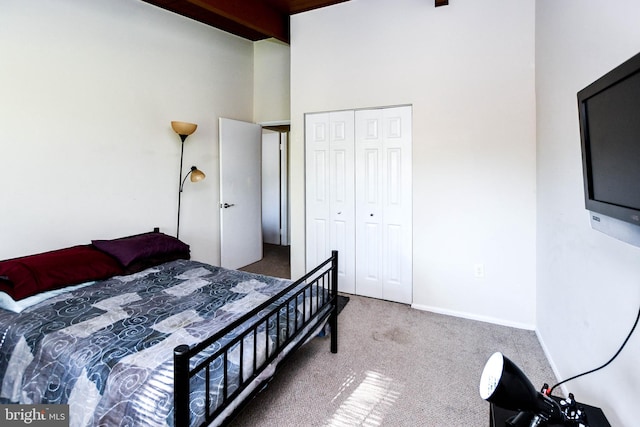 carpeted bedroom featuring a closet, beamed ceiling, and a high ceiling